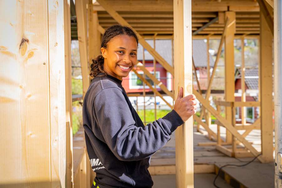 Blid jente smiler imøtekommende på byggeplass.